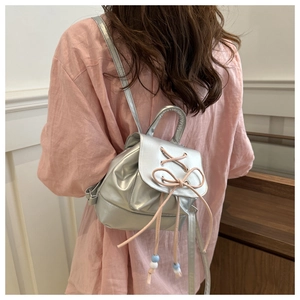 Detail of silver metallic mini backpack with pink bow and decorative beads accents