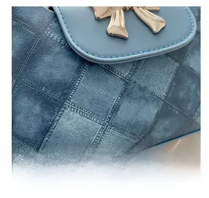 Close-up of blue denim quilted handbag with light blue leather trim and golden bow