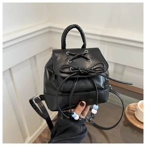 Detail of a mini black backpack featuring decorative bow lacing and blue-white beads