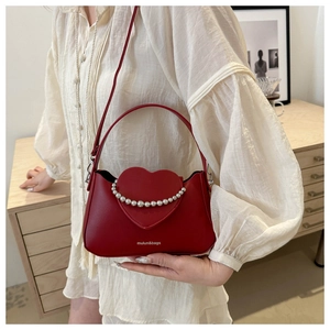 Macro view of a red heart crossbody bag with silver bead trim and a sleek leather finish