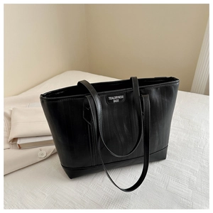 Dettaglio borsa shopper nera con trama verticale ed etichetta del marchio cucita