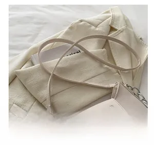 Dettaglio borsa a spalla in pelle PU crema con fiocco metallico e catena argento