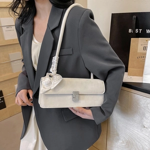 Elegant cream shoulder bag with S-shaped buckle and scarf bow on grey blazer