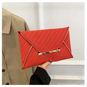 Détail de pochette enveloppe rouge avec texture chevrons et boucle en métal doré miroir