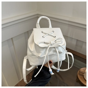 Close-up of white mini backpack with decorative bow and colorful beads details