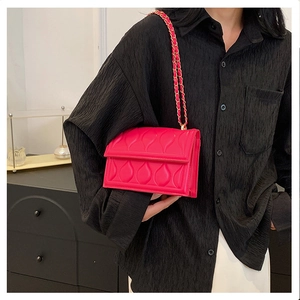 Détail du sac bandoulière matelassé rouge rose avec texture nervurée et chaîne