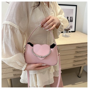 Detail of light pink crossbody bag with heart-shaped flap and silver bead trim decorations