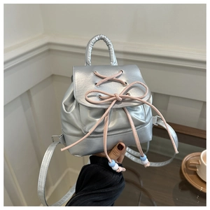 Detail of silver mini backpack with a pink bow and pleated handle in hand