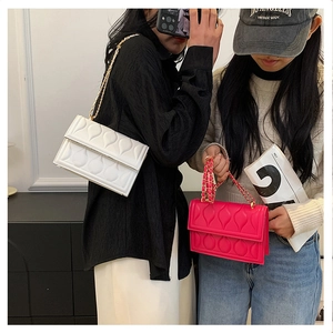 Sac à rabat matelassé avec chaîne dorée en blanc et rose porté par le mannequin