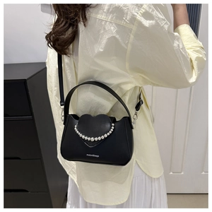 Close-up of black matte leather mini bag with heart flap and white pearl bead chain