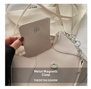 Dettaglio della chiusura magnetica della borsa a tracolla panna con catena in argento