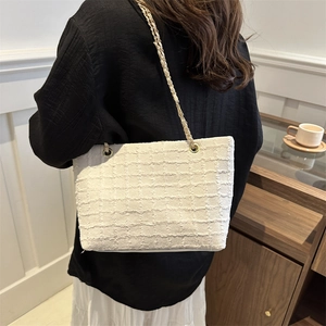 Elegant white tweed tote bag with gold chain strap shown in a modern interior setting