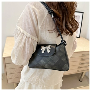 Detail of a vintage-style quilted underarm bag featuring a silver metal bow buckle