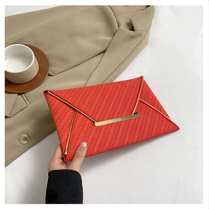 Détail de pochette enveloppe rouge avec texture tissée et fermoir en métal doré