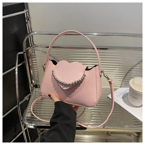 Detail view of a pink heart-shaped crossbody bag featuring silver bead chain and matte leather