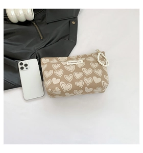 Close-up of khaki heart-print canvas makeup bag with elegant pearl zipper charm decoration