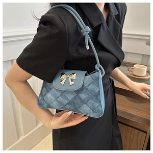 Close-up of light blue shoulder bag featuring a silver bow buckle and knotted strap detail