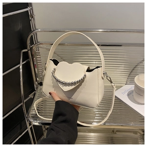 Detailed view of white mini square bag with heart flap and silver pearl chain accessory