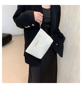 Detail of white canvas clutch with heart pattern and pearl handle on a black dress