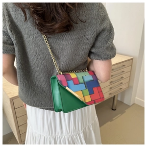 Detail of green crossbody bag with colorful geometric patterns and gold chain strap