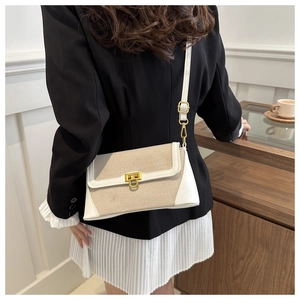 Detail shot of a canvas and leather bag with a gold twist lock and a thin shoulder strap