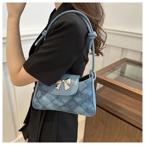 Detail of blue quilted denim underarm bag with silver bow buckle and knotted shoulder strap