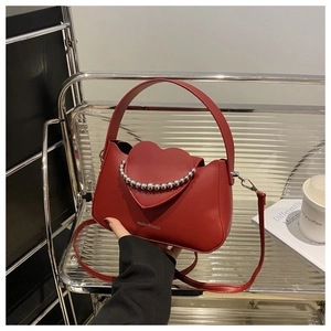 Detail of red heart-shaped handbag with silver beaded chain and adjustable shoulder strap