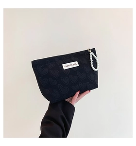 Detail of black heart-embossed canvas makeup bag with pearl handle and Fashion Bag label