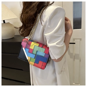Detail showing colorful geometric tetris pattern flap and gold chain on black crossbody bag