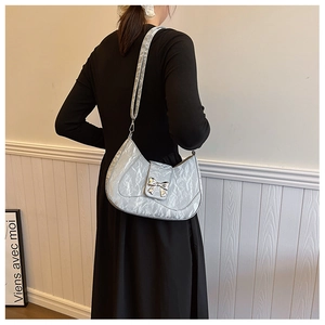Detail of silver crescent shoulder bag with metallic finish and bow metal buckle