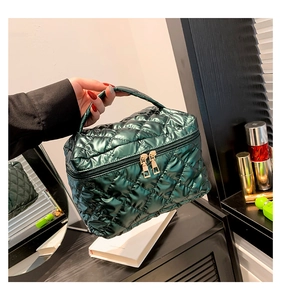 Dettaglio della borsa da trucco trapuntata verde scuro metallizzato con cerniere dorate e manico