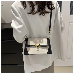 Detail of vintage cream canvas baguette bag with black leather trim and gold metal lock