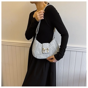 Detail of silver metallic crescent bag featuring pleated texture and metal bow ornament