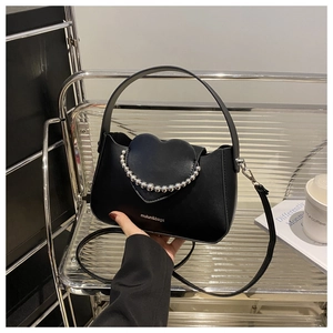 Detail view of black heart flap handbag featuring a silver beaded chain and top handle