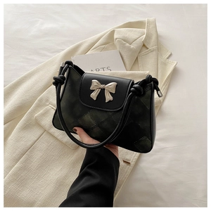 Chic checkered shoulder bag with silver bow hardware on elegant beige suit background