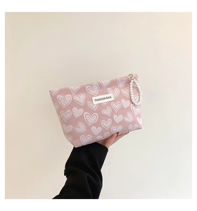 Detail of pink canvas heart pattern bag with beaded pearl handle and metal zipper closure