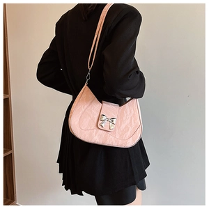 Detail of pink pleated leather shoulder bag featuring a silver bow metal buckle on a model