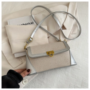 Detail of cream woven texture and silver leather trim on an elegant baguette bag