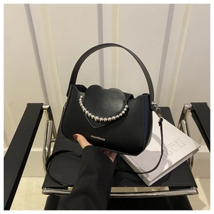 Close-up of heart-shaped flap with silver bead chain trim on matte black handbag