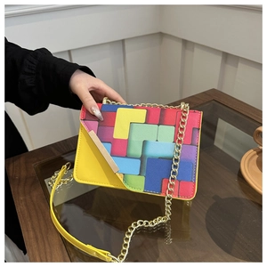 Detail of colorful geometric pattern flap on yellow crossbody bag with gold chain