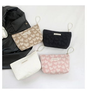 Detail view of heart pattern canvas makeup bags with elegant pearl handles in four colors