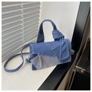 Detail of patchwork denim crossbody bag featuring contrast stitching and a knotted top handle