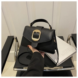 Detail of black lychee grain leather handbag with vintage gold buckle and top handle