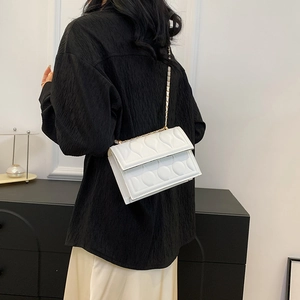 Sac bandoulière blanc matelassé chic avec chaîne dorée porté par un mannequin