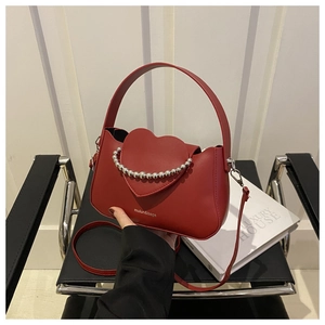 Detail of red heart flap bag featuring silver beaded handle and white printed logo
