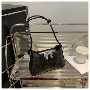 Detail of black shoulder bag featuring silver metal bow and diamond quilted texture