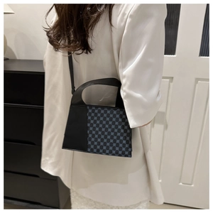 Détail d'un sac bandoulière trapèze chic avec un motif géométrique bicolore à pois