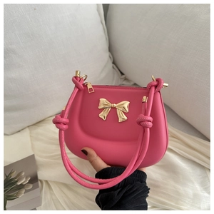 Close-up of pink handbag with golden bow buckle and braided handle on white bedding
