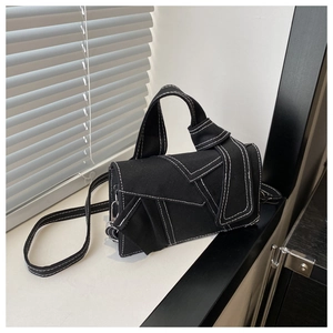 Detail of black canvas handbag showing white contrast stitching and unique knotted handle