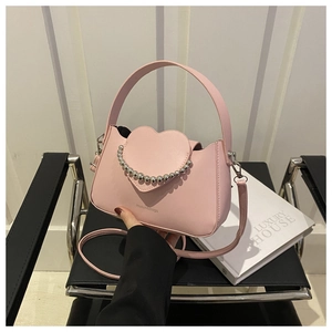 Detailed view of pink heart-shaped crossbody bag with silver bead trim and leather texture